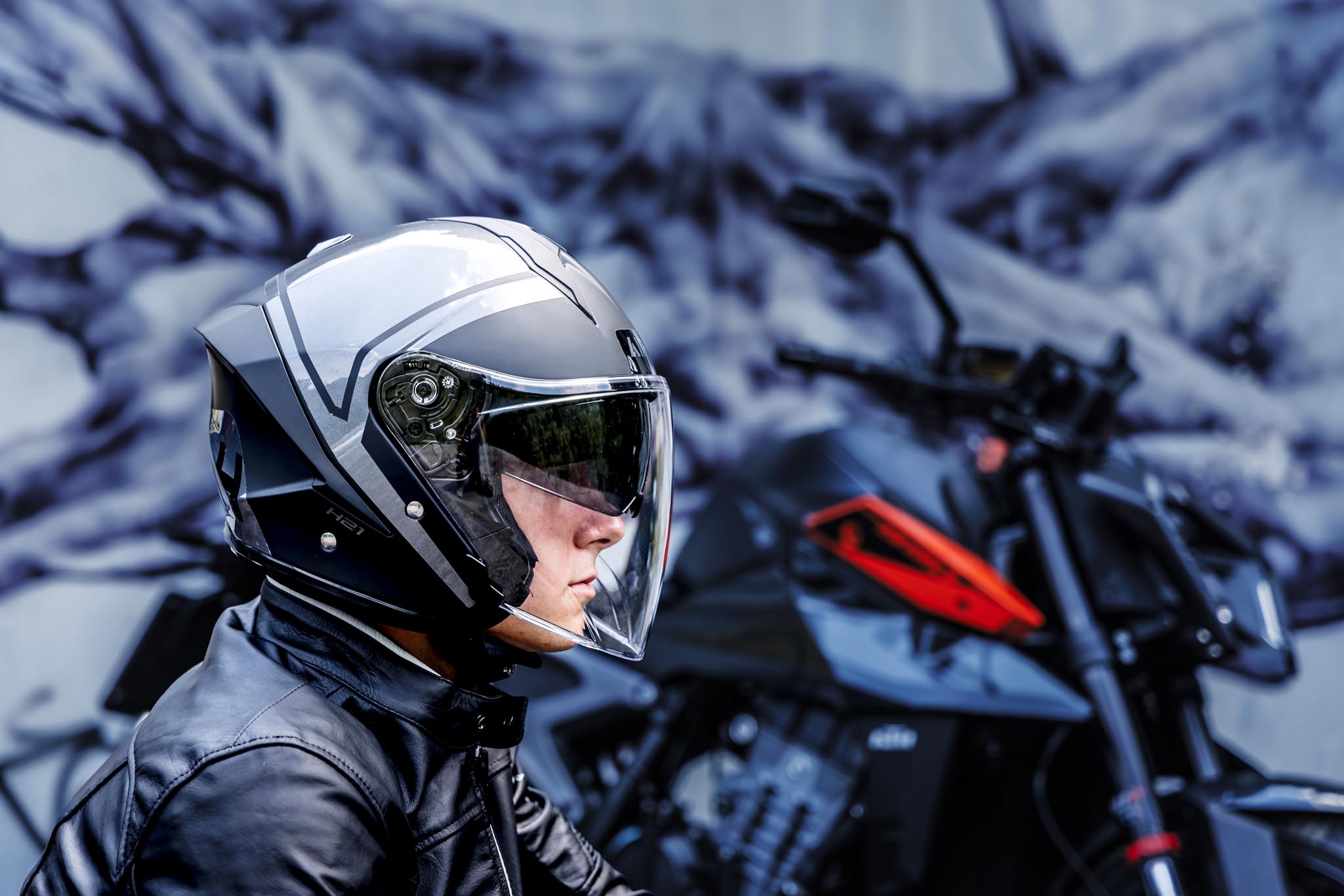 Motard portant le casque jet AIROH H.21 avec visière transparente devant une moto