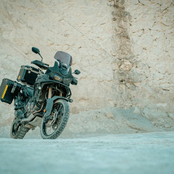 Moto trail équipée de crash bars roulant sur une piste près d’une grotte