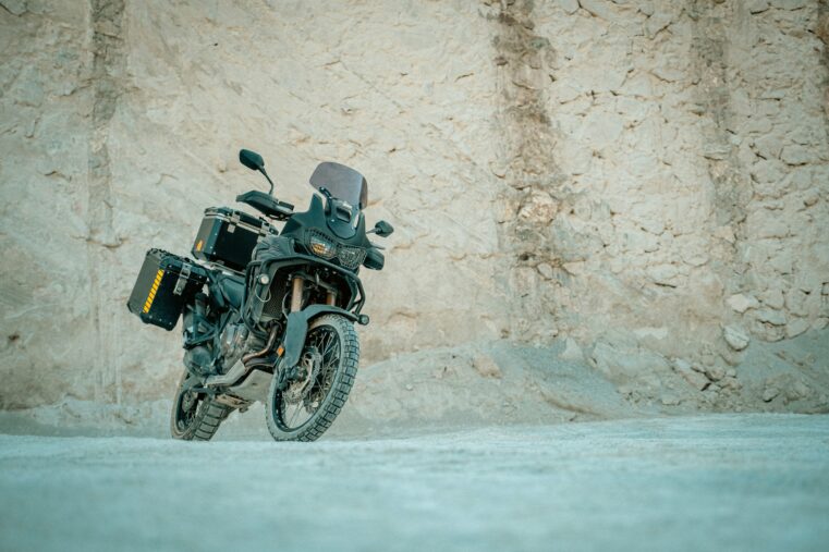 Moto trail équipée de crash bars roulant sur une piste près d’une grotte